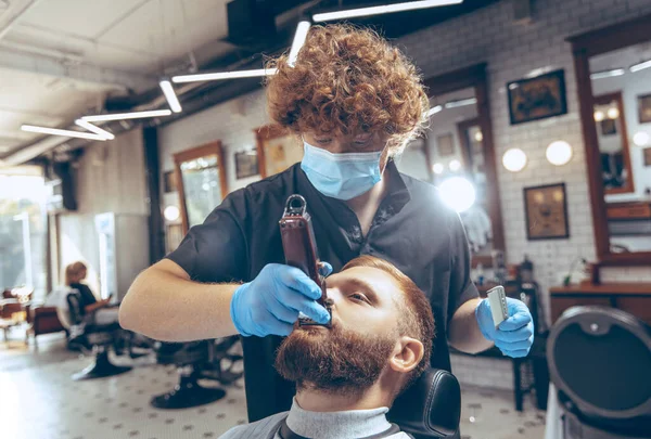 Man getting hair cut at the barbershop wearing mask during coronavirus pandemic — Stock Photo, Image