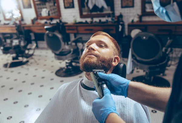 Man getting hair cut at the barbershop wearing mask during coronavirus pandemic