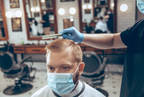 Man getting hair cut at the barbershop wearing mask during coronavirus pandemic — Stock Photo, Image