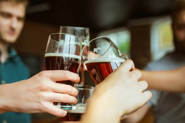 Joven grupo de amigos bebiendo cerveza, divirtiéndose, riéndose y celebrando juntos. Primer plano tintineo vasos de cerveza — Foto de Stock