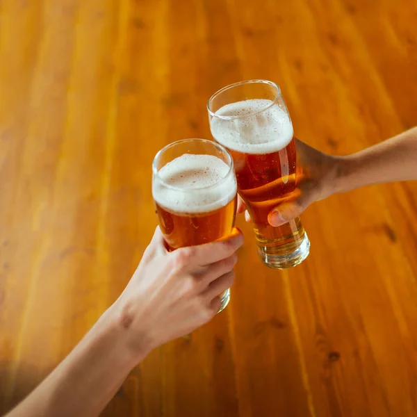 Joven grupo de amigos bebiendo cerveza, divirtiéndose, riéndose y celebrando juntos. Primer plano tintineo vasos de cerveza — Foto de Stock