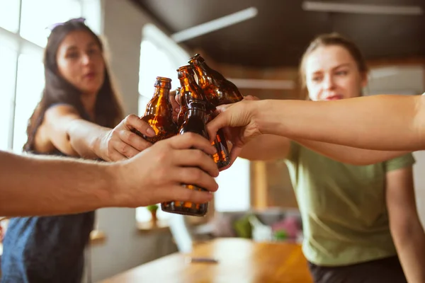 Mladá skupina přátel pije pivo, baví se, směje se a slaví spolu. Zavřít cinkající láhve od piva — Stock fotografie