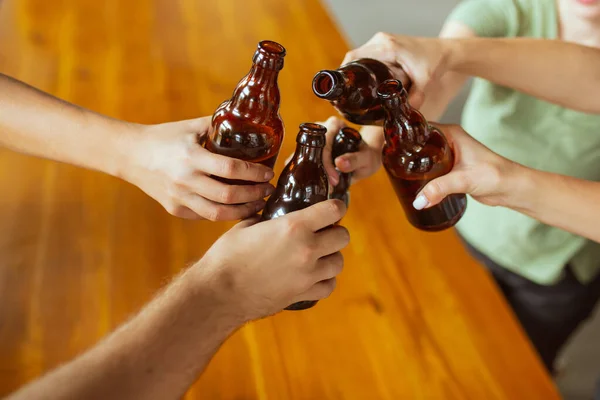 Молода група друзів п'є пиво, розважається, плекає і святкує разом. Крупним планом кмітливі пляшки пива — стокове фото
