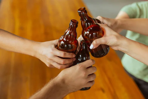 Mladá skupina přátel pije pivo, baví se, směje se a slaví spolu. Zavřít cinkající láhve od piva — Stock fotografie