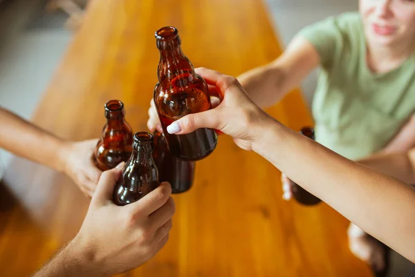 Jovem grupo de amigos bebendo cerveja, se divertindo, rindo e comemorando juntos. Fechar as garrafas de cerveja — Fotografia de Stock