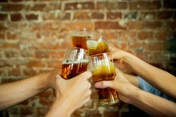 Junge Freunde trinken Bier, haben Spaß, lachen und feiern zusammen. Großaufnahme klirrende Biergläser — Stockfoto