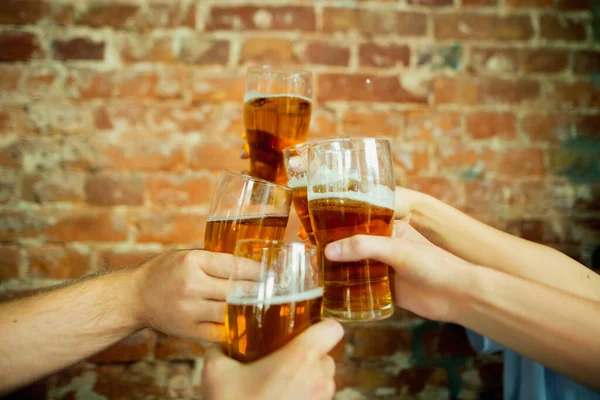 Junge Freunde trinken Bier, haben Spaß, lachen und feiern zusammen. Großaufnahme klirrende Biergläser — Stockfoto