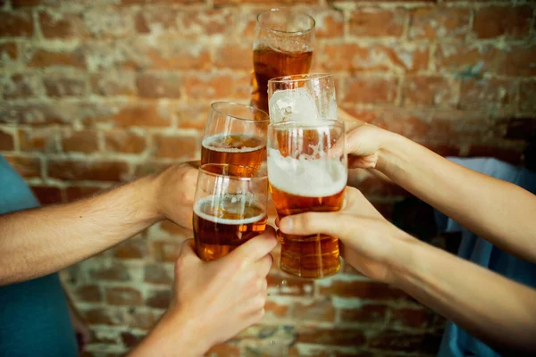 Junge Freunde trinken Bier, haben Spaß, lachen und feiern zusammen. Großaufnahme klirrende Biergläser — Stockfoto