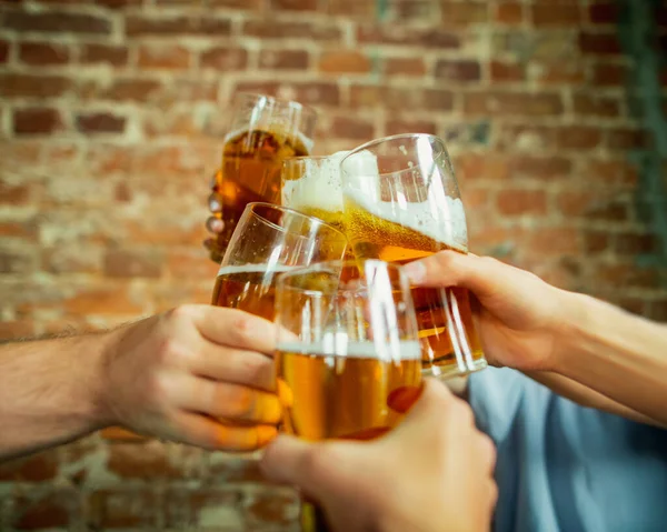 Giovani amici che bevono birra, si divertono, ridono e festeggiano insieme. Chiudere clinking bicchieri di birra — Foto Stock