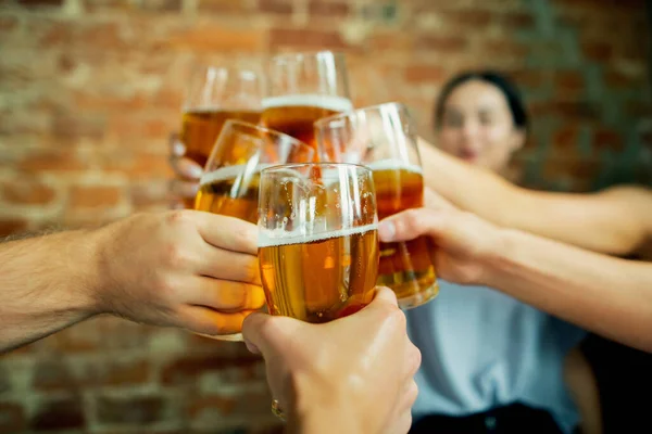 Mladá skupina přátel pije pivo, baví se, směje se a slaví spolu. Zavřít cinkající pivní sklenice — Stock fotografie