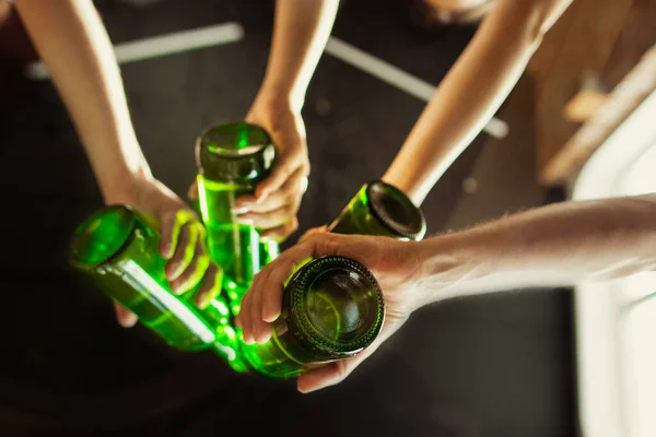 Bir grup genç arkadaş bira içiyor, eğleniyor, gülüyor ve birlikte kutluyorlar. Bira şişelerini tıkırdat. — Stok fotoğraf