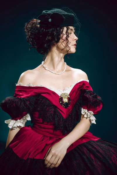 Young woman as Anna Karenina on dark blue background. Retro style, comparison of eras concept.