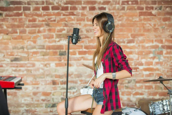 Vrouw in hoofdtelefoon die muziek opneemt, zingt of internetles geeft terwijl ze op zolder of thuis zit — Stockfoto