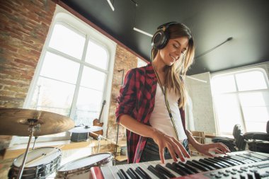 Kadın müzik kaydediyor, şarkı söylüyor ve piyano çalıyor. Çatı katında ya da evde dururken.