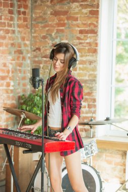 Kadın müzik kaydediyor, şarkı söylüyor ve piyano çalıyor. Çatı katında ya da evde dururken.