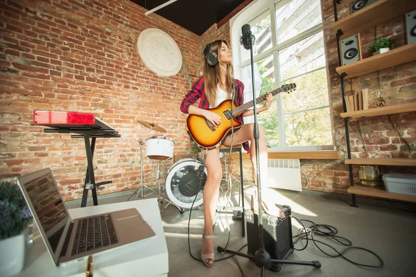 Vrouw in hoofdtelefoon die muziek opneemt, zingt of internetles geeft terwijl ze op zolder of thuis zit — Stockfoto