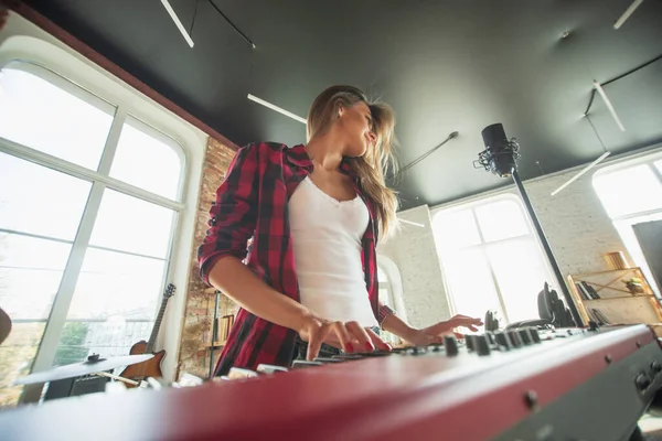 Mujer grabando música, cantando y tocando el piano mientras está de pie en el lugar de trabajo o en casa — Foto de Stock