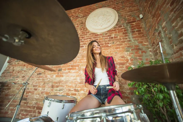 Kadın iş yerinde ya da evde otururken müzik kaydediyor, şarkı söylüyor ve davul çalıyor.