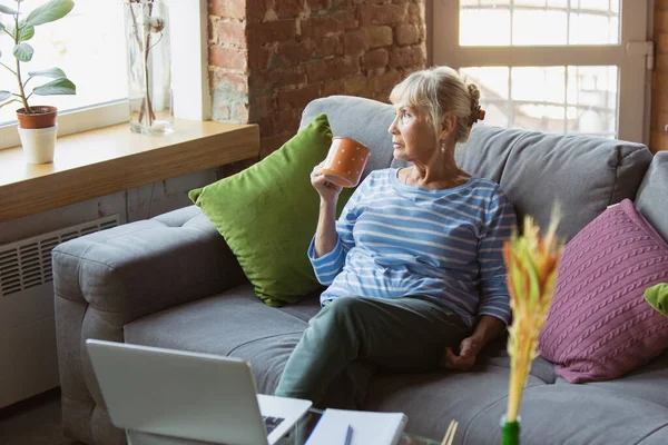 Mujer mayor estudiando en casa, recibiendo cursos en línea — Foto de Stock
