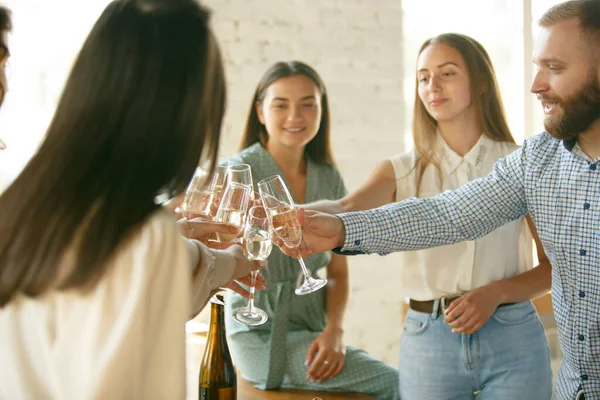 Les gens claquent des verres avec du vin ou du champagne. Heureux amis joyeux célèbrent les vacances, la réunion. Gros plan des amis souriants, mode de vie — Photo