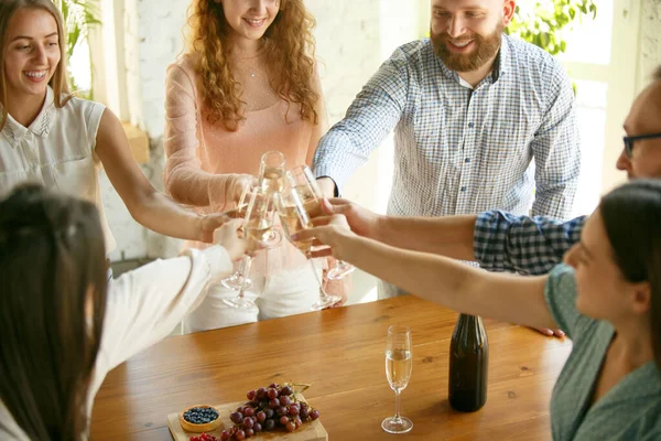 Les gens claquent des verres avec du vin ou du champagne. Heureux amis joyeux célèbrent les vacances, la réunion. Gros plan des amis souriants, mode de vie — Photo