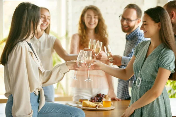 Les gens claquent des verres avec du vin ou du champagne. Heureux amis joyeux célèbrent les vacances, la réunion. Gros plan des amis souriants, mode de vie — Photo