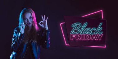 Karanlık arka planda neon ışıklı genç bir kadının portresi. İnsan duyguları, Kara Cuma, siber pazartesi, alışverişler, satışlar, finans konsepti. Neoned harfleri..