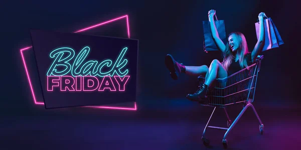 Portrait of young woman in neon light on dark backgound. The human emotions, black friday, cyber monday, purchases, sales, finance concept. Neoned lettering. — Stock Photo, Image