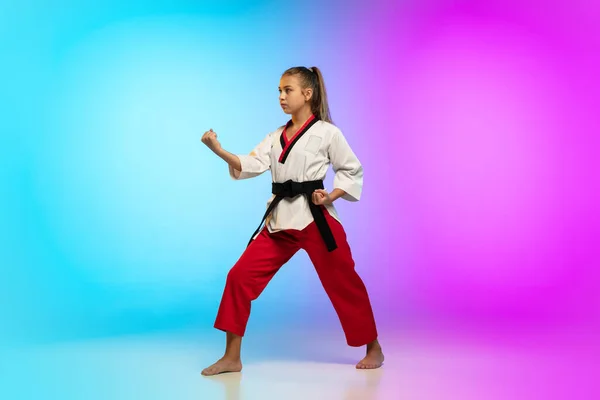 Karatê, menina taekwondo com cinto preto isolado no fundo gradiente em luz de néon — Fotografia de Stock