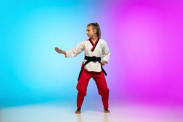 Karatê, menina taekwondo com cinto preto isolado no fundo gradiente em luz de néon — Fotografia de Stock