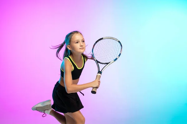 Klein tennis meisje in zwart sportwear geïsoleerd op gradiënt achtergrond in neon licht — Stockfoto