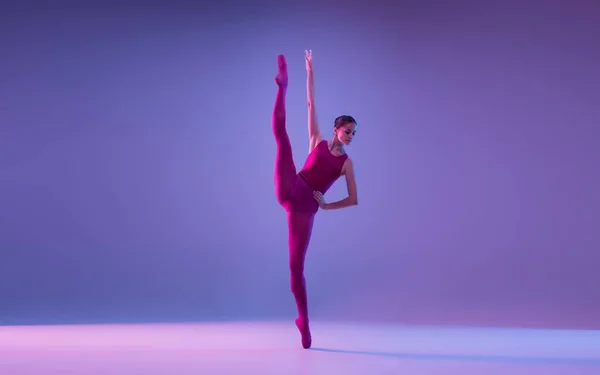 Jovem e graciosa bailarina de balé isolado em fundo estúdio roxo em luz de néon — Fotografia de Stock