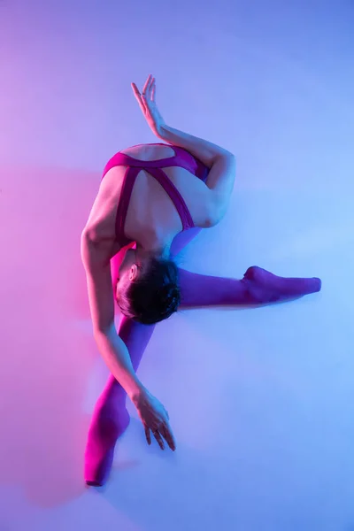 Jovem e graciosa bailarina de balé isolado em fundo estúdio roxo em luz de néon — Fotografia de Stock