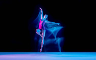 Genç ve zarif balerin, siyah stüdyo arka planında karışık ışıkla izole edilmiş.