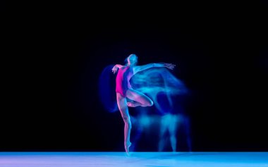 Genç ve zarif balerin, siyah stüdyo arka planında karışık ışıkla izole edilmiş.