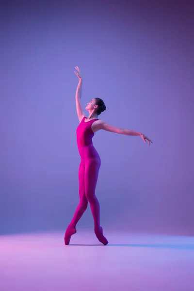 Jovem e graciosa bailarina de balé isolado em fundo estúdio roxo em luz de néon — Fotografia de Stock