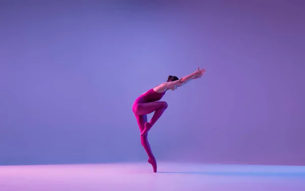 Young and graceful ballet dancer isolated on purple studio background in neon light — Stock Photo, Image