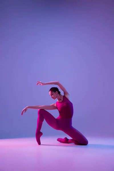 Jovem e graciosa bailarina de balé isolado em fundo estúdio roxo em luz de néon — Fotografia de Stock