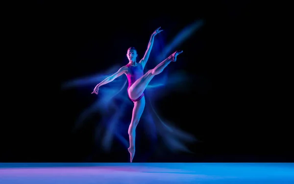 在霓虹灯混合灯光下，年轻而优雅的芭蕾舞演员被隔离在黑人工作室的背景下 — 图库照片