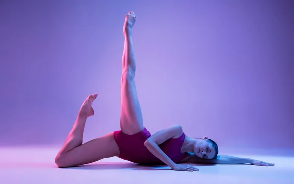 Νεαρή και χαριτωμένη χορεύτρια μπαλέτου απομονωμένη σε μωβ φόντο στούντιο σε νέον φως — Φωτογραφία Αρχείου