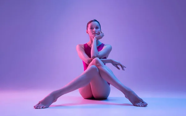 Νεαρή και χαριτωμένη χορεύτρια μπαλέτου απομονωμένη σε μωβ φόντο στούντιο σε νέον φως — Φωτογραφία Αρχείου