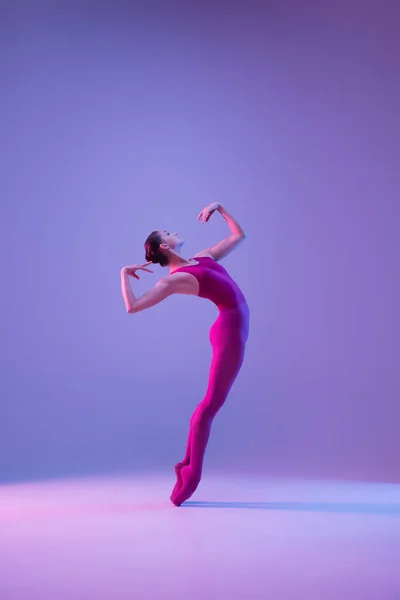 Jovem e graciosa bailarina de balé isolado em fundo estúdio roxo em luz de néon — Fotografia de Stock