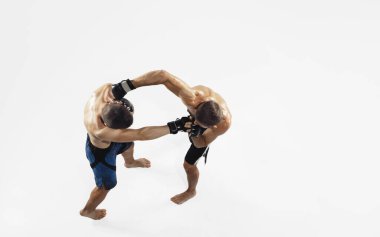 Beyaz stüdyo arka planında izole edilmiş iki profesyonel MMA dövüşçüsü, dinamik ve hareketli. Üst görünüm