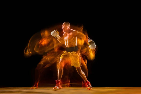 Professionelles Boxtraining isoliert auf schwarzem Studiohintergrund in gemischtem Licht — Stockfoto