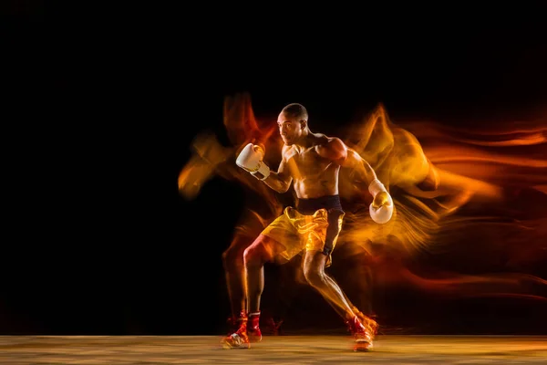 Professional boxer training isolated on black studio background in mixed light — Stock Photo, Image