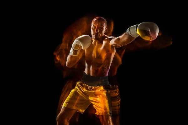 Professional boxer training isolated on black studio background in mixed light — Stock Photo, Image