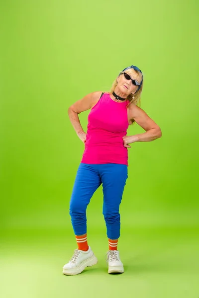 Senior woman in ultra trendy attire isolated on bright green background — Stock Photo, Image
