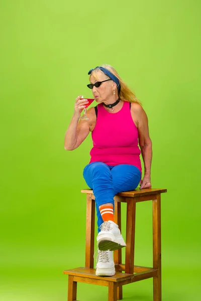 Senior woman in ultra trendy attire isolated on bright green background — Stock Photo, Image