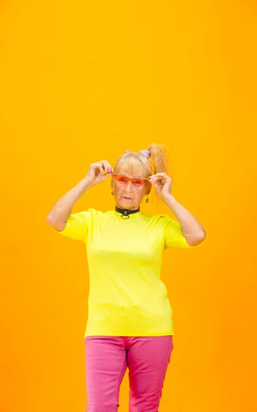 Старшая женщина в ультра модном наряде изолирована на ярком оранжевом фоне — стоковое фото
