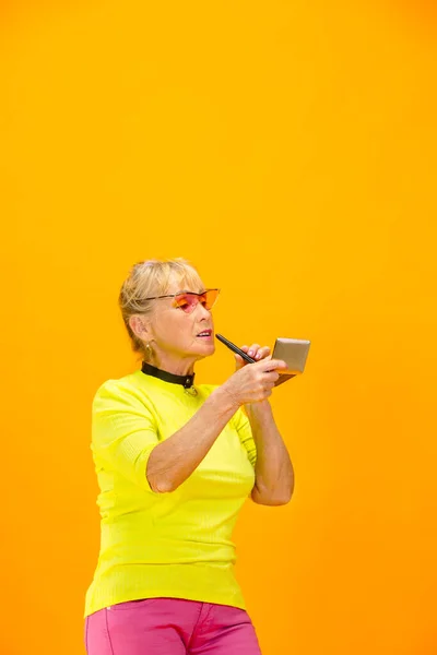 Senior woman in ultra trendy attire isolated on bright orange background — Stock Photo, Image